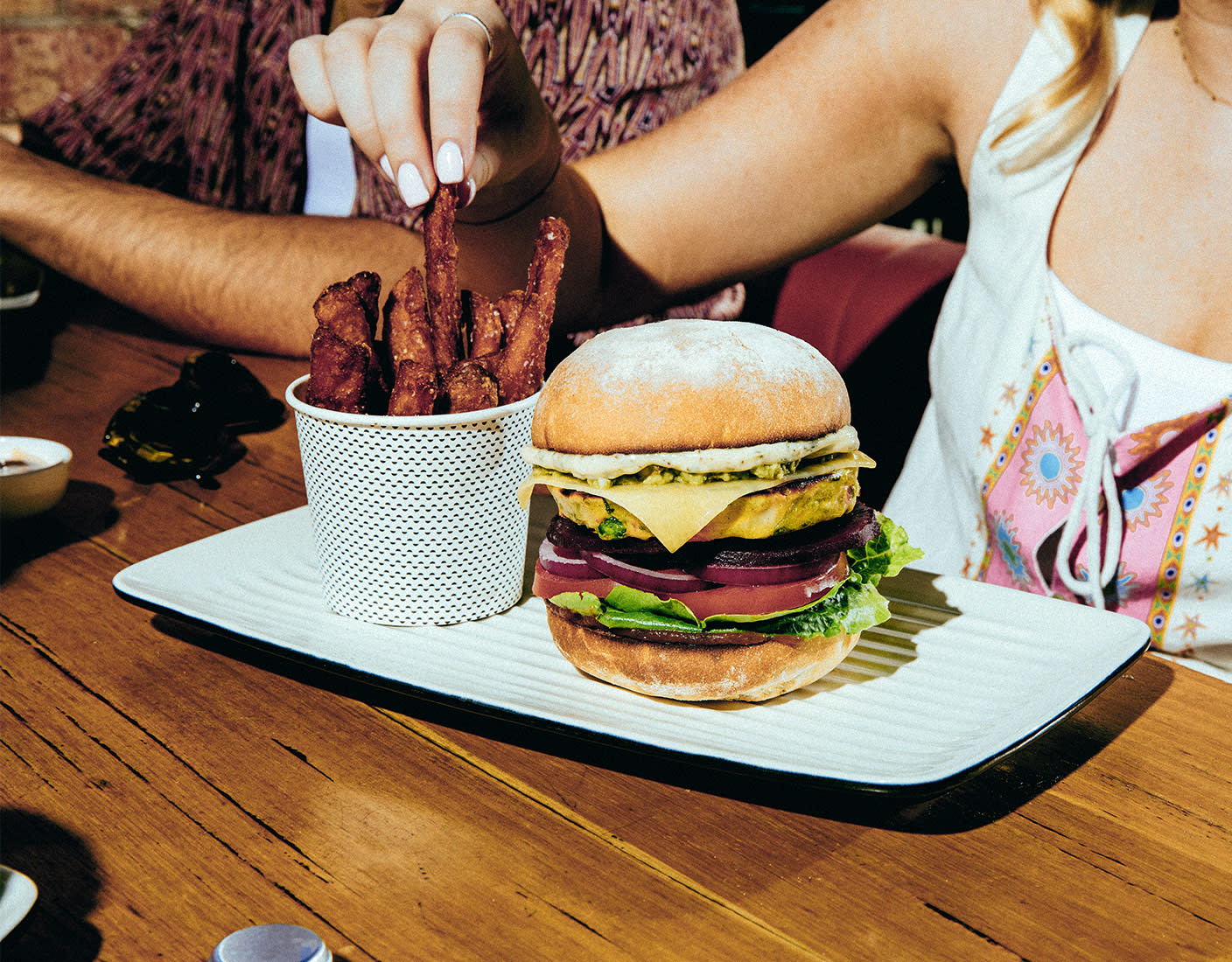 A woman presents a plate of hamburger and fries in a restaurant setting.